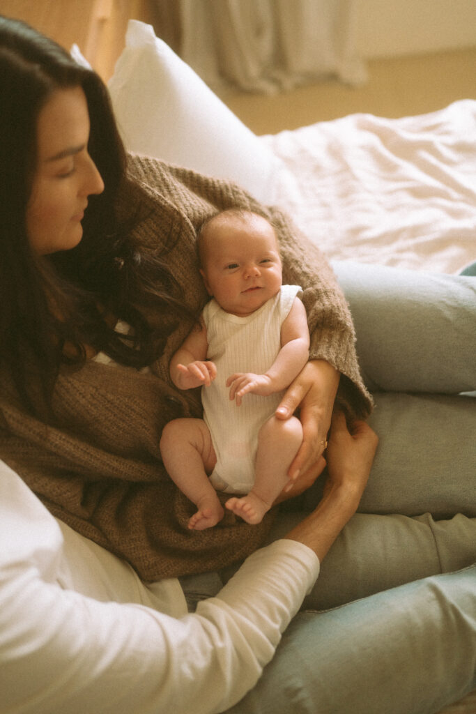 Parents holding baby Maisie in a sun-drenched living room.