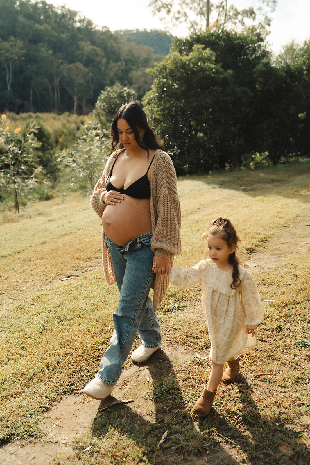 Expectant mother and daughter walking outside