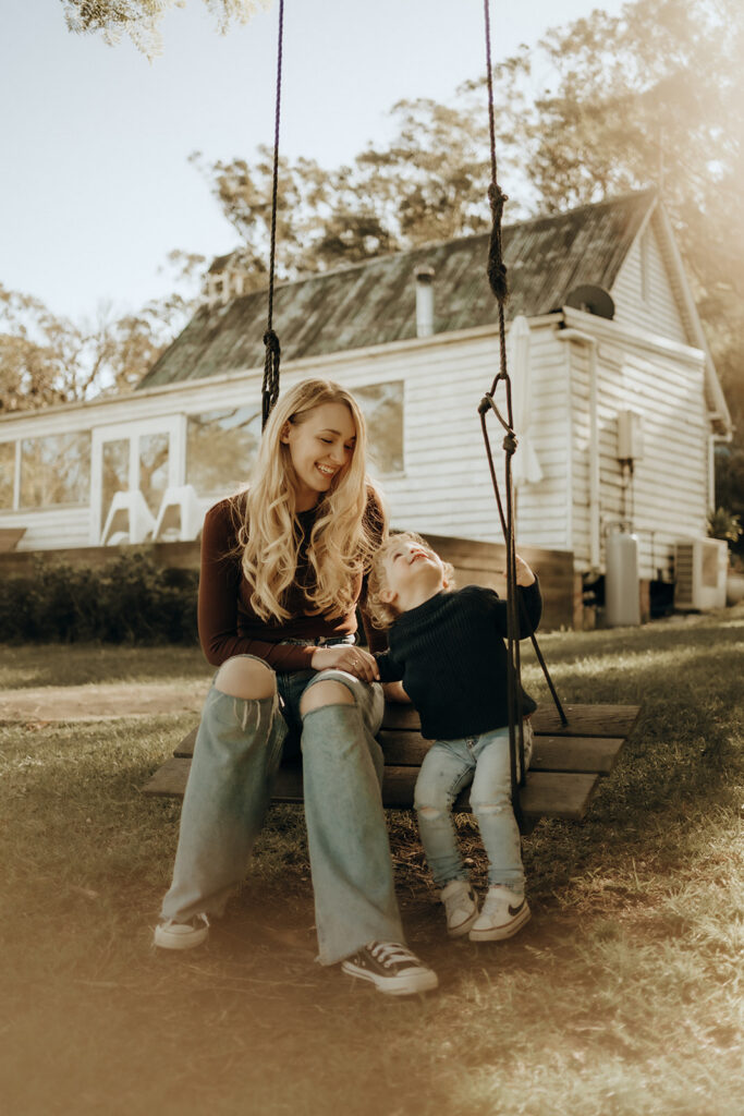 Mother sitting on a swing with a toddler during a By Joey Motherhood Mini session.