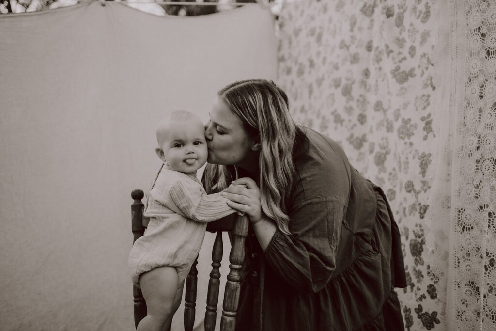 Mother kissing her baby during a By Joey Motherhood Mini session.